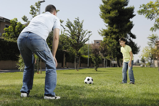 father and son playing football in urban park
