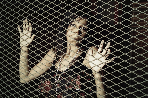 Young woman behind a metal fence &#8211; es