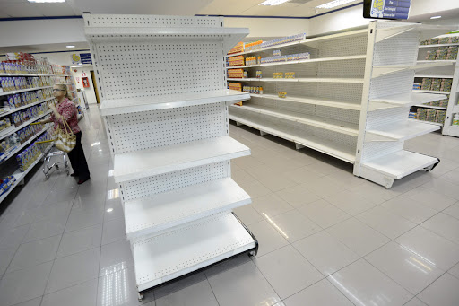 A woman walks next to empty shelves in a supermarket in Caracas &#8211; es