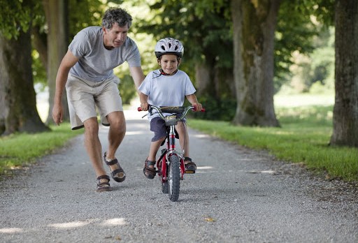 papá enseñando a un niño a andar en bicicleta