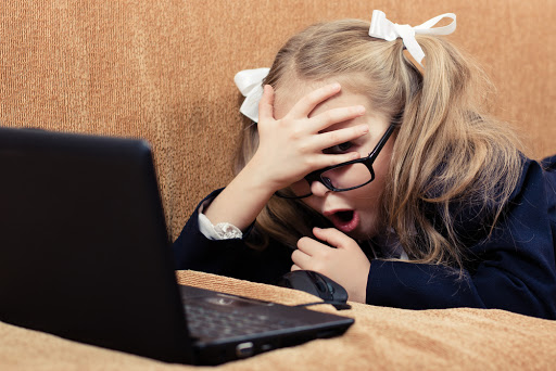 Cute schoolgirl with glasses and laptop in a state of shock &#8211; es
