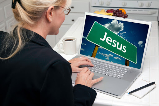 Woman In Kitchen Using Laptop with Jesus Road Sign on Screen. &#8211; es