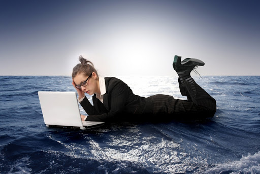 businesswoman with laptop sinking in the sea &#8211; es