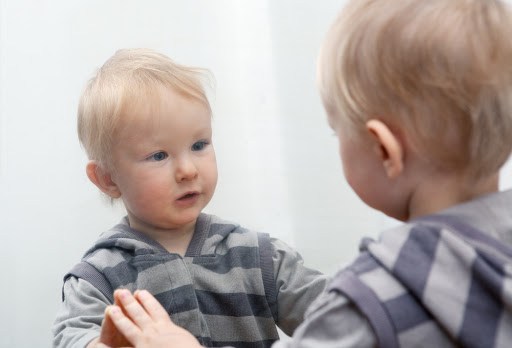 Small child looking to mirror at his face &#8211; es