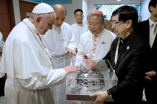 Pope Francis receiving a crown made of barbed wire from the border between South and North Korea &#8211; es