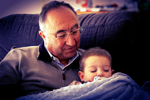 Abuelo tiene su nieto dormido en brazos