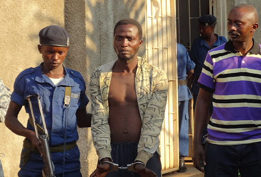 BURUNDI, Bujumbura : A Burundian policeman escorts suspect Christian Claude Butoyi (C) after he was arrested in Bujumbura for the murder of three Italian nuns on September 9, 2014 &#8211; es