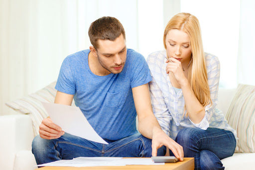 Busy couple with papers and calculator at home &#8211; es