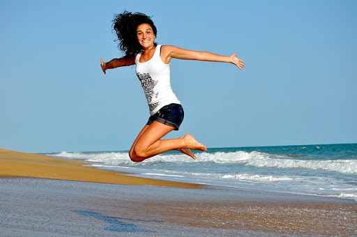 mujer saltando a orillas del mar