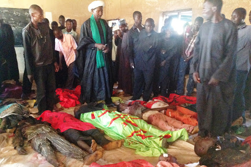 Mustapha Lawan Nasidi, the leader of the Shi&#8217;a Muslim community (C) stands over bodies of sect members at Madrasatul Fudiyya seminary in the northeast Nigerian town of Potiskum on on November 3, 2014. &#8211; es