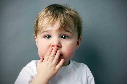 A child with hand in front of mouth &#8211; es