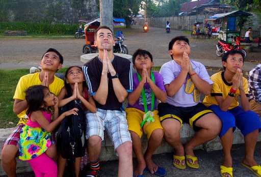 Joven misionero rezando con un grupo de niños