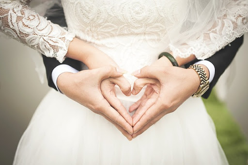 pareja de recién casados formando un corazón con sus manos
