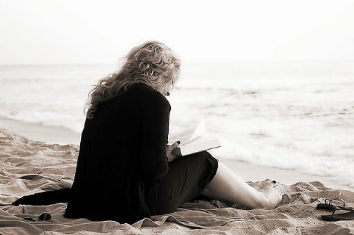 mujer leyendo a orillas del mar