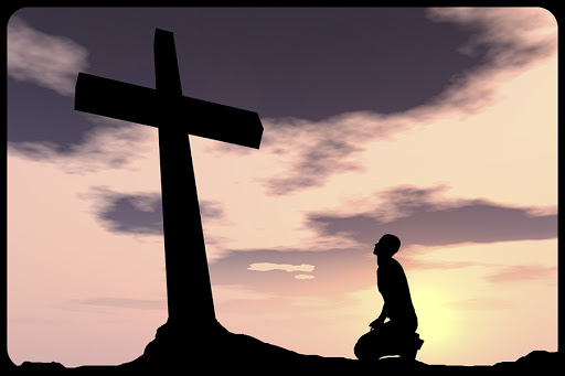 Silhouette of a man praying under the cross © Design36 / Shutterstock &#8211; es