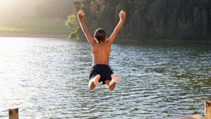 Young boy jumping into lake © Monkey Business Images / Shutterstock – es