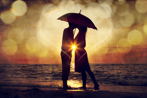 Couple kissing under umbrella at the beach in sunset © Masson / Shutterstock &#8211; es