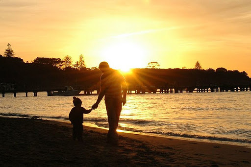 padre e hijo caminando por la playa al atardecer