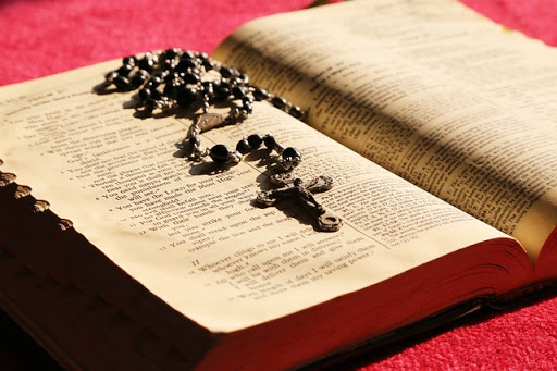 Biblia y rosario, fondo rojo