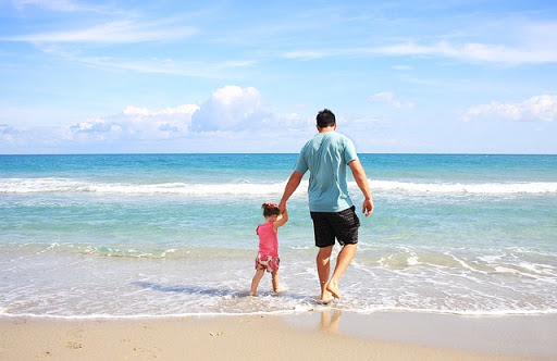 padre e hija caminando a orillas del mar
