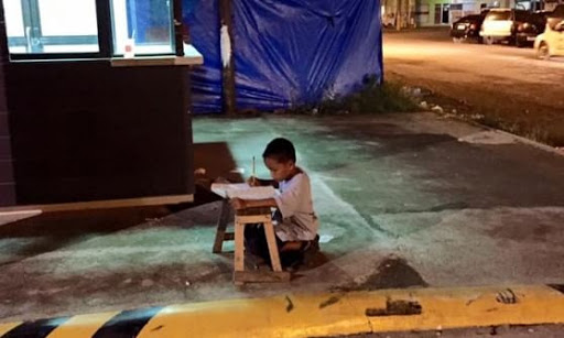 Enfant qui fait ses devoirs dans la rue &#8211; es