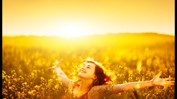 Young happy woman in canola field on sunset.