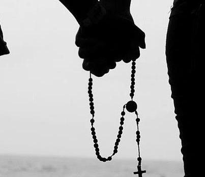 manos juntas orando con rosario