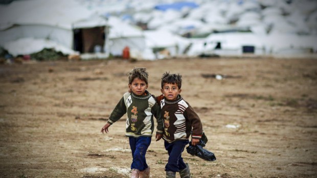 Syrian boys, whose family fled their home in Idlib, walk to thei