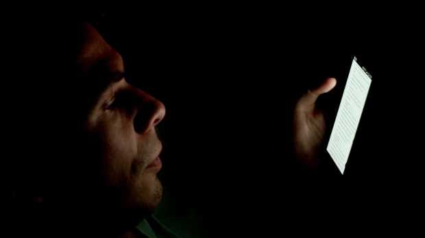 hombre mirando el smartphone en la oscuridad