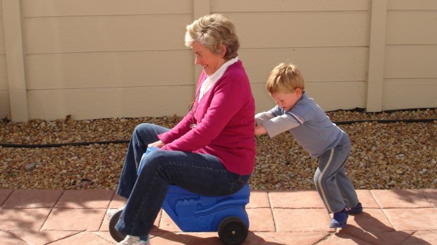 child_pushing_grandmother_on_plastic_tricycle.jpg