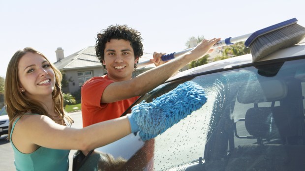 Portrait of a happy multiethnic couple washing car together