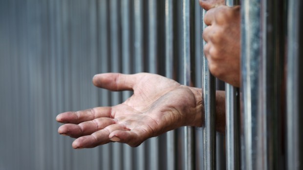 web-hands-jail-prison-man-shutterstock_334321733-sakhorn-ai