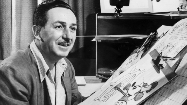 Mr Walt Disney sits at his drawing board in his studio, drawing a sketch of Mickey Mouse