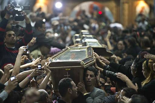 Egyptian Copts carry four coffins down the aisle of the Virgin Mary Coptic Christian church in Cairo's working class neighbourhood of Al-