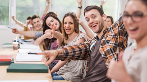 Cheerful students celebrating in classroom and looking at camera