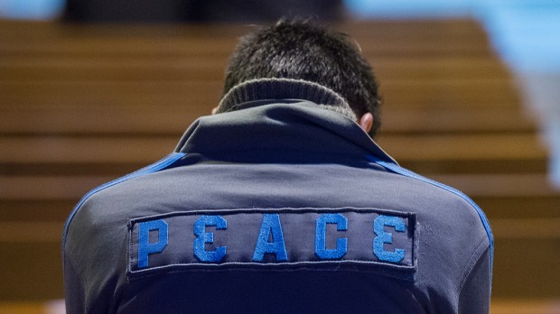 hero-peace-young-man-jacket-pew-back-marcin-mazur-catholicnews-org
