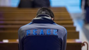 web-peace-young-man-jacket-pew-back-marcin-mazur-catholicnews-org