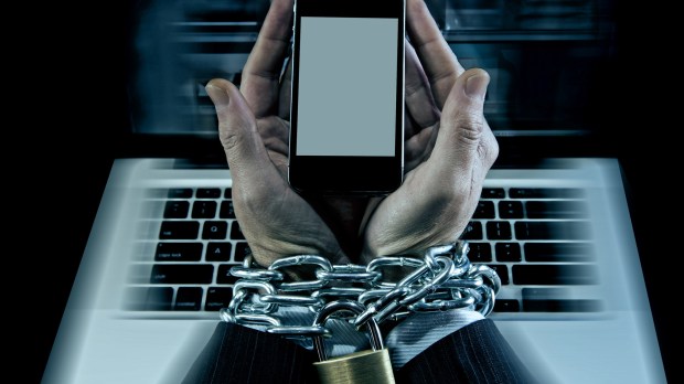 Hands of caucasian businessman addicted to mobile phone bond and locked with iron chain wrists in smartphone internet addiction and slave to online network addict concept