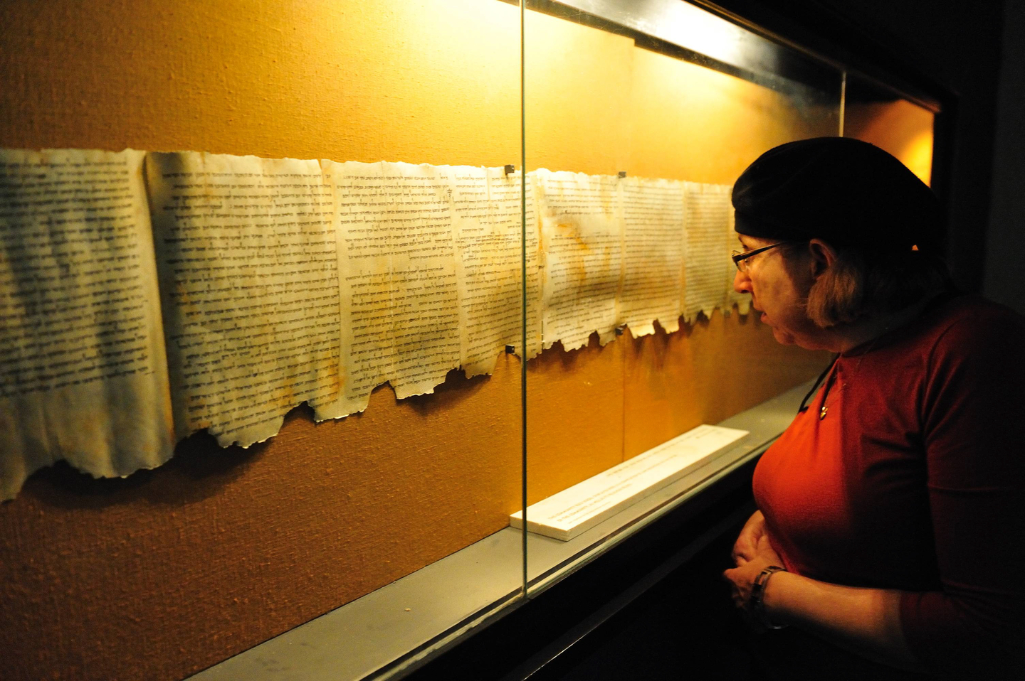 QUMRAN, ISRAEL – DEC 14 2008:Woman looks at the Dead Sea Scrolls on display at the caves of Qumran.The Dead Sea Scrolls were discovered in Qumran caves between the years 1947 and 1956.