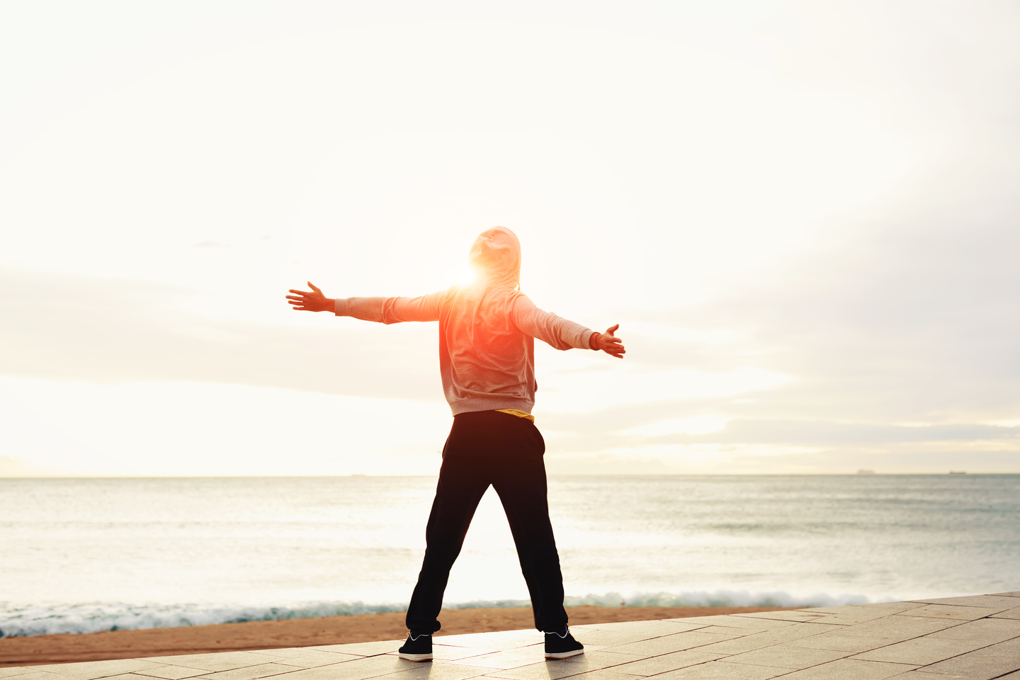 Freedom, relax and harmony in nature, Rear view of a young guy with his arms outstretched at the seaside standing next to the sea, happiness emotional concept