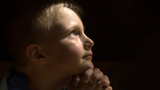 web3-young-child-praying-dark-background-oksana-mizina-shutterstock_303404972