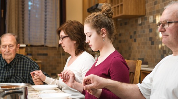 WEB3 FAMILY PRAYING GENERATIONS DINNER HOLDING HANDS Shutterstock