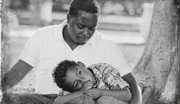 African American Father Worried About His Mixed Race Son as They Sit in the Park.