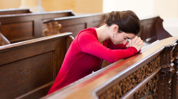 WEB3 WOMAN CHURCH PRAYING SAD CRYING Shutterstoc