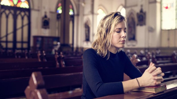 WEB3 WOMAN PRAYING CHURCH MASS BIBLE Shutterstock