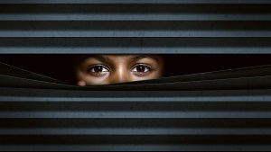 Child looks through window blinds