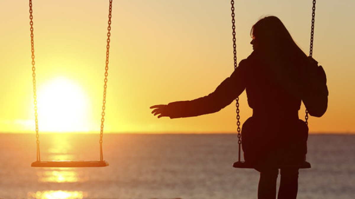 single-woman-swinging-beach-sunset