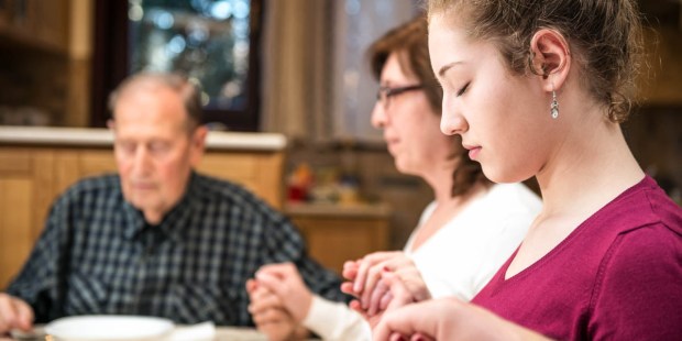 FAMILY PRAYING AT DINNER