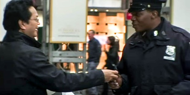 MAN HANDING A POLICE OFFICER A CANDLE
