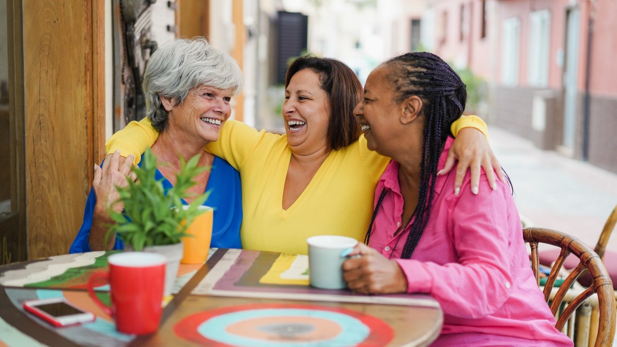 Amistad Amigos adultos multirraciales divirtiéndose abrazando en el bar al aire libre mientras toman café juntos